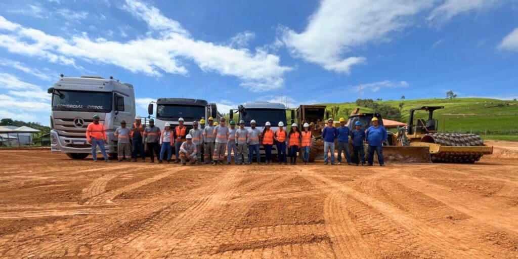 Equipe da Gali reunida em obra de terraplanagem, com caminhões e máquinas pesadas ao fundo, durante etapa de preparação do solo para subestação de energia.