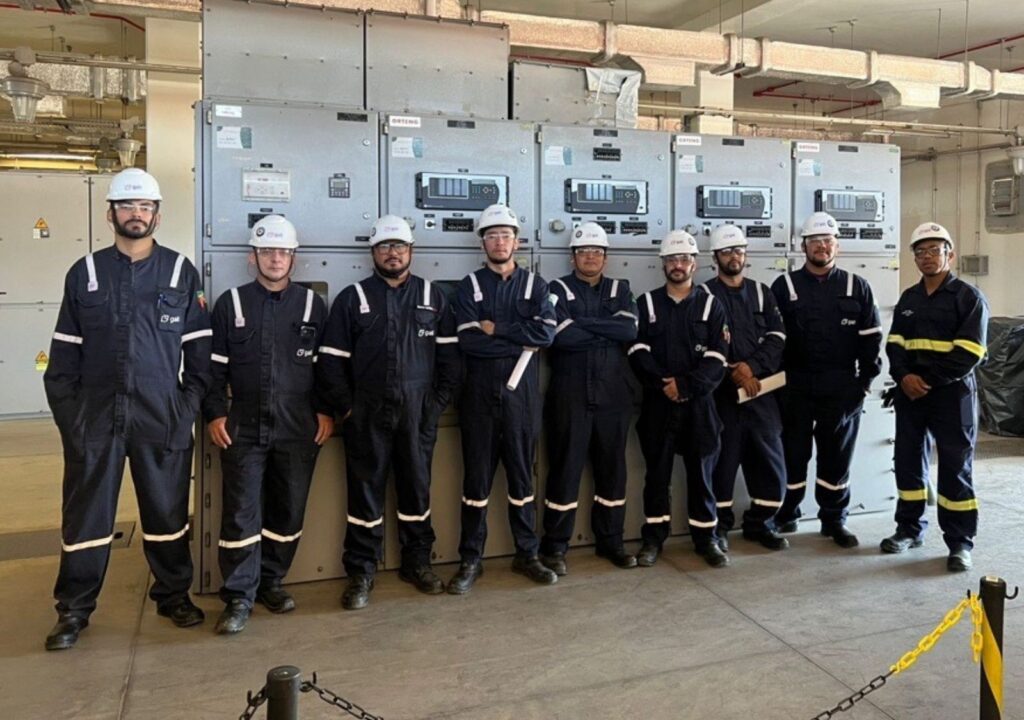 Equipe técnica da Gali Energia com EPIs em frente a painel elétrico durante serviço de comissionamento.
