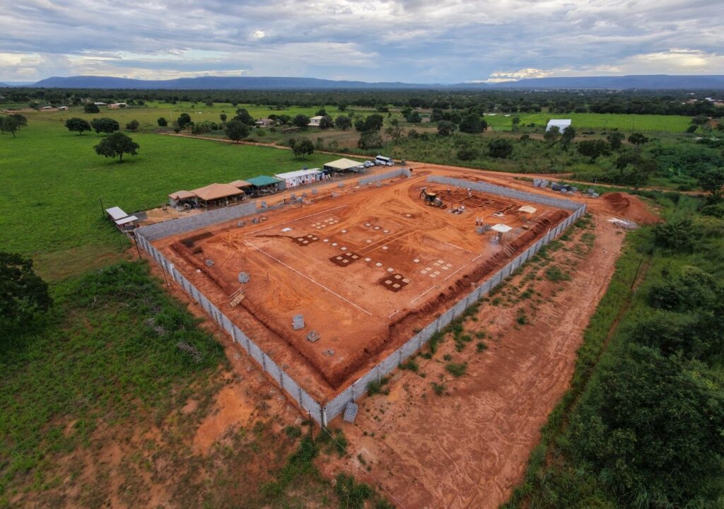 Vista aérea de canteiro de obras da SE Arinos 3, mostrando conclusão das fundações com escavadeiras e equipes trabalhando em infraestrutura energética.